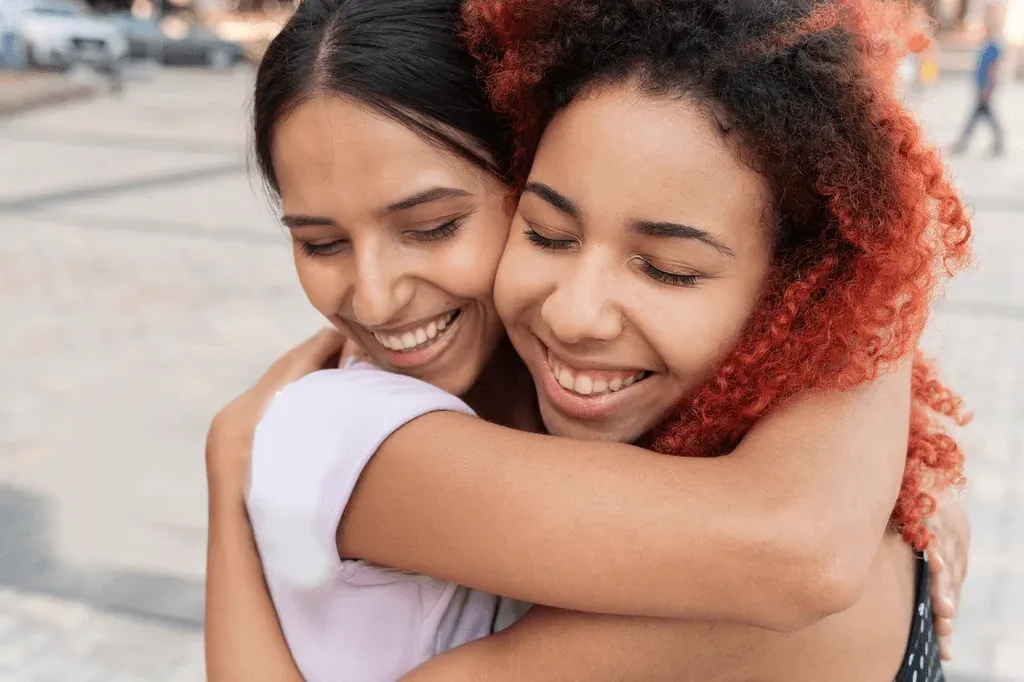 Duas jovens sorrindo e se abraçando